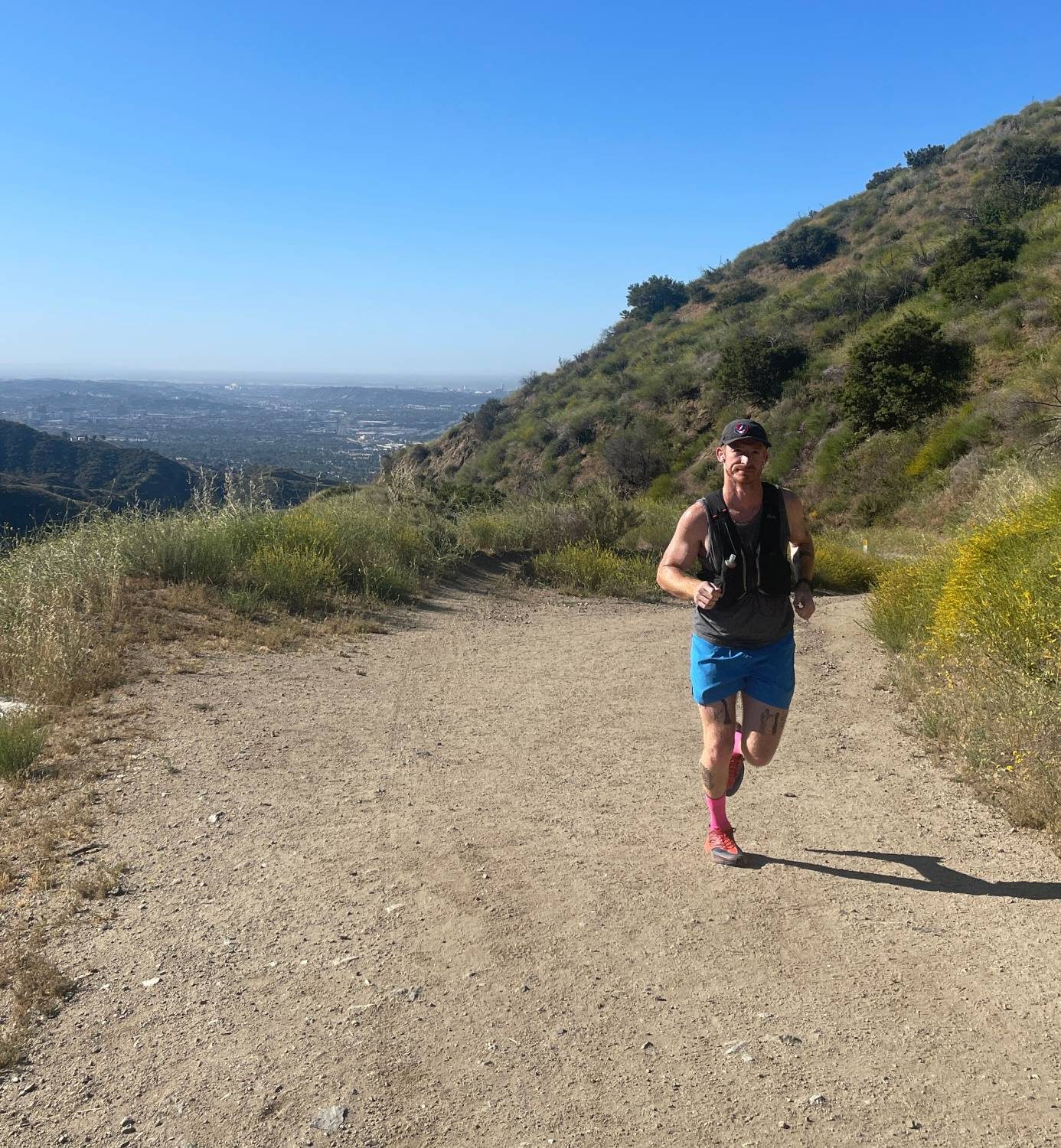 Austin running on a mountain trail above the city